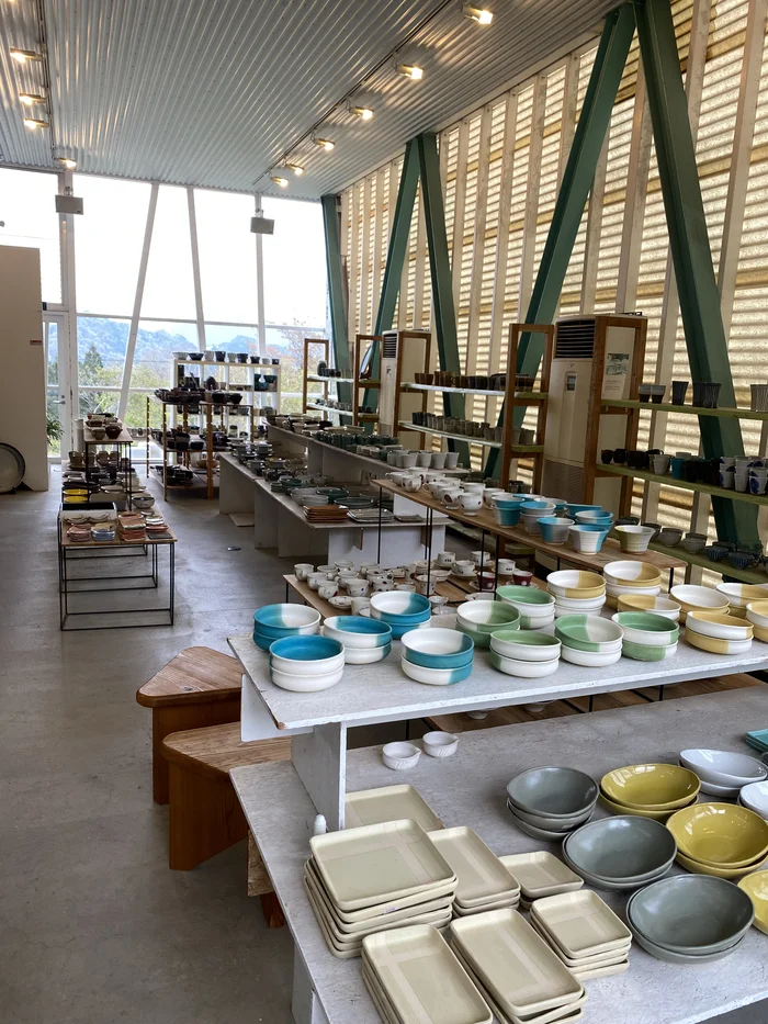 カラフルな器が棚に並ぶ広い1階フロア、A字梁の下