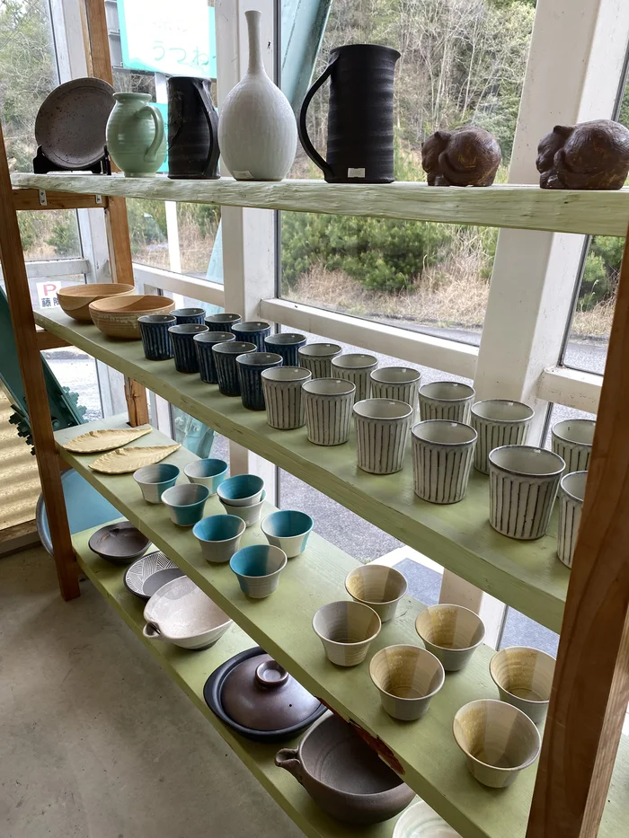 窓際の棚にカップや花瓶、小さな信楽焼の狸が並ぶ