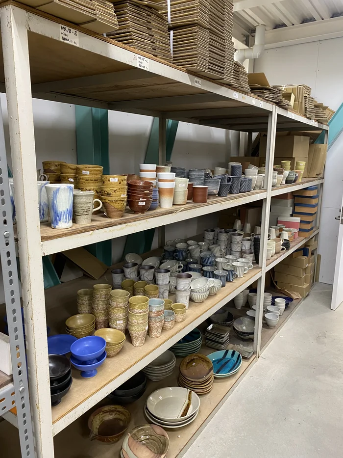 スチール棚にカップや皿が整然と並ぶ在庫エリア