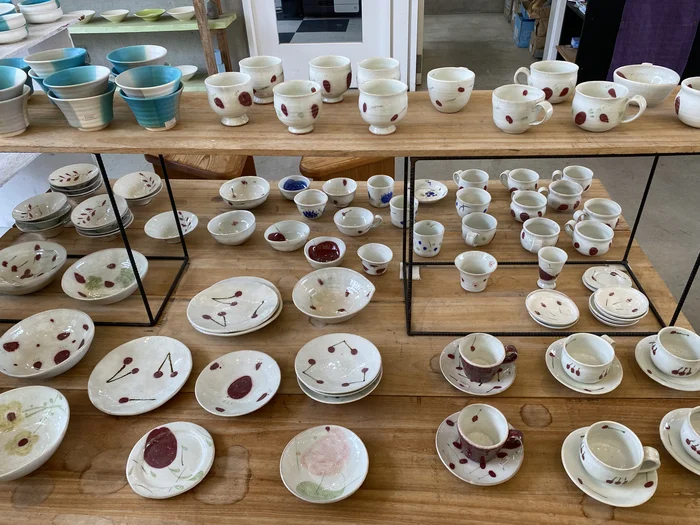 赤い模様が特徴的な作家ものの皿やカップが並ぶ