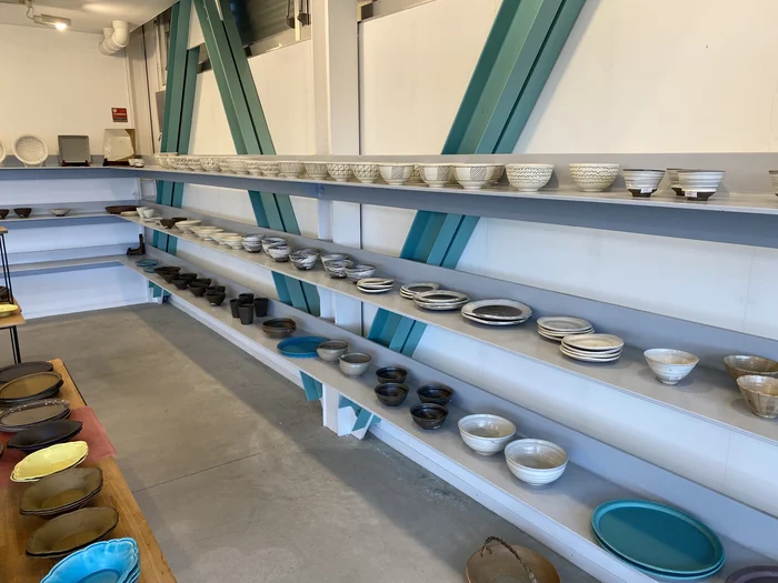 緑のA字梁の下、壁面棚に茶碗が整然と並ぶ