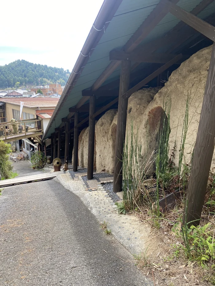 屋根付きの柱に支えられた登り窯の外壁、土壁が連なる