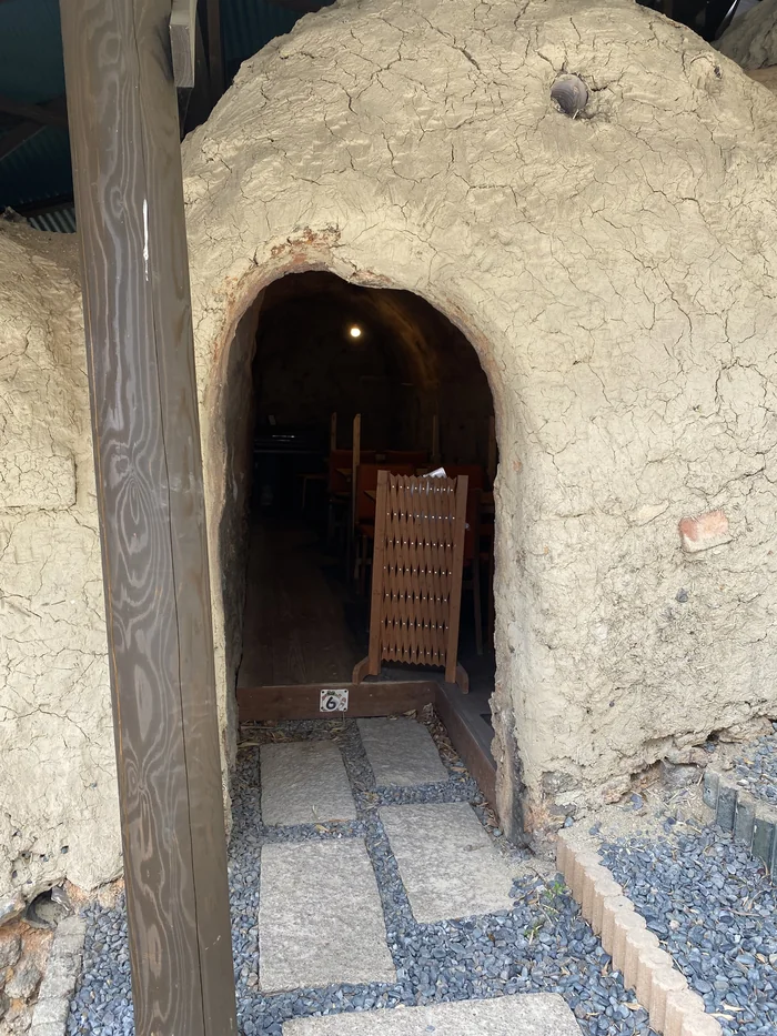 アーチ型の土壁の窯の入口、奥にテーブルが見える