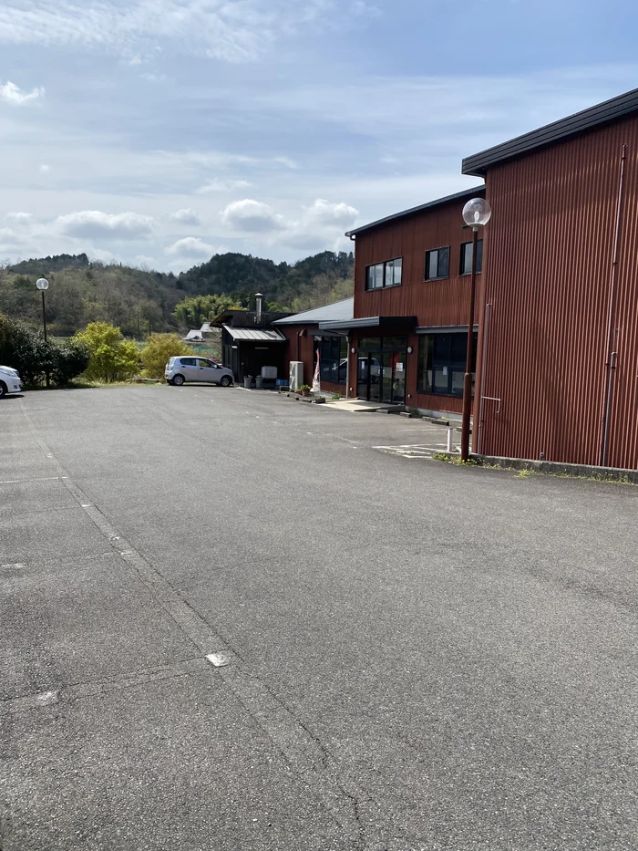 茶色の外壁の店舗側面と広い駐車場