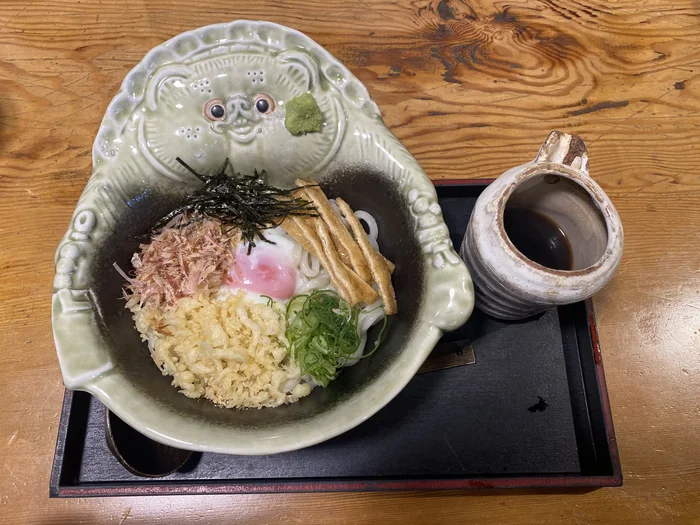 狸の顔を模した器に盛られた狸うどん、温泉卵や天かすがたっぷり