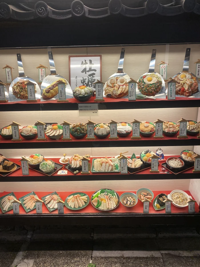 ショーケースに並ぶお好み焼きや焼きそばの食品サンプル