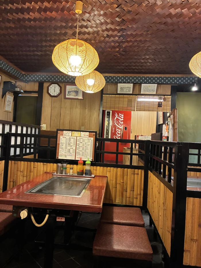 籠ランプと鉄板テーブルが並ぶレトロな店内