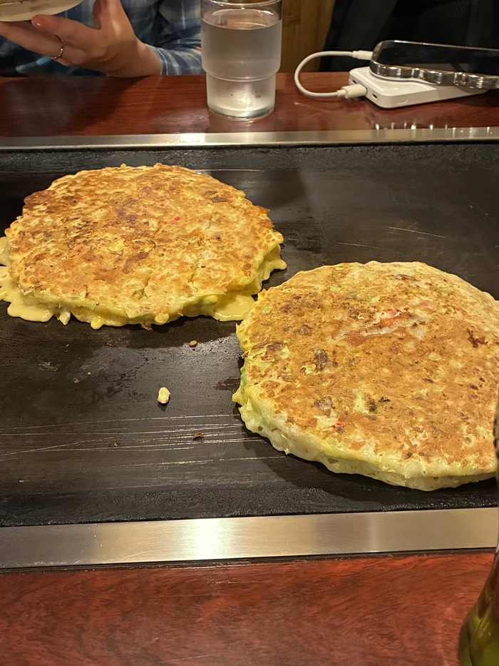 目の前の鉄板で焼かれる2枚のお好み焼き