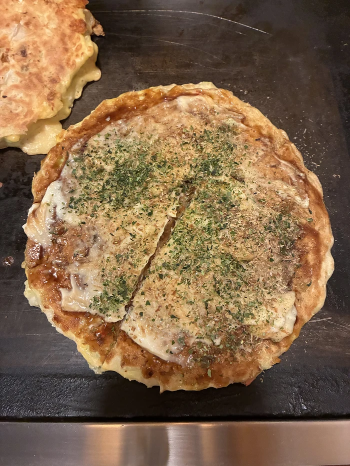 ソースと青のりがかかった焼き上がりのお好み焼き