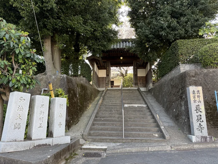 石段の上に建つ寺の山門と弘法大師と刻まれた石柱