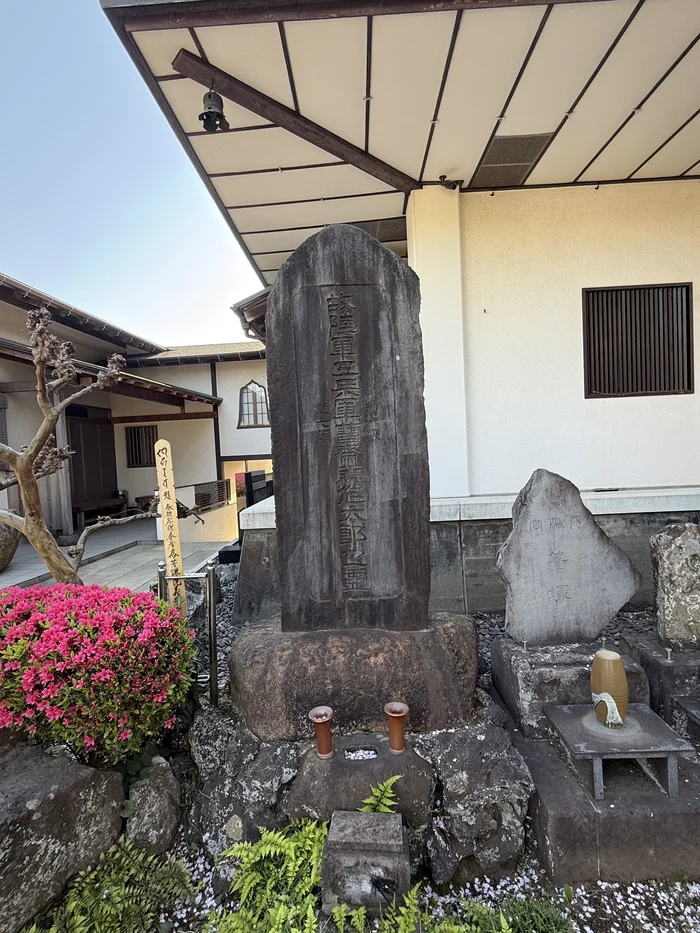 ツツジの花の咲く一角に立つ古い石碑