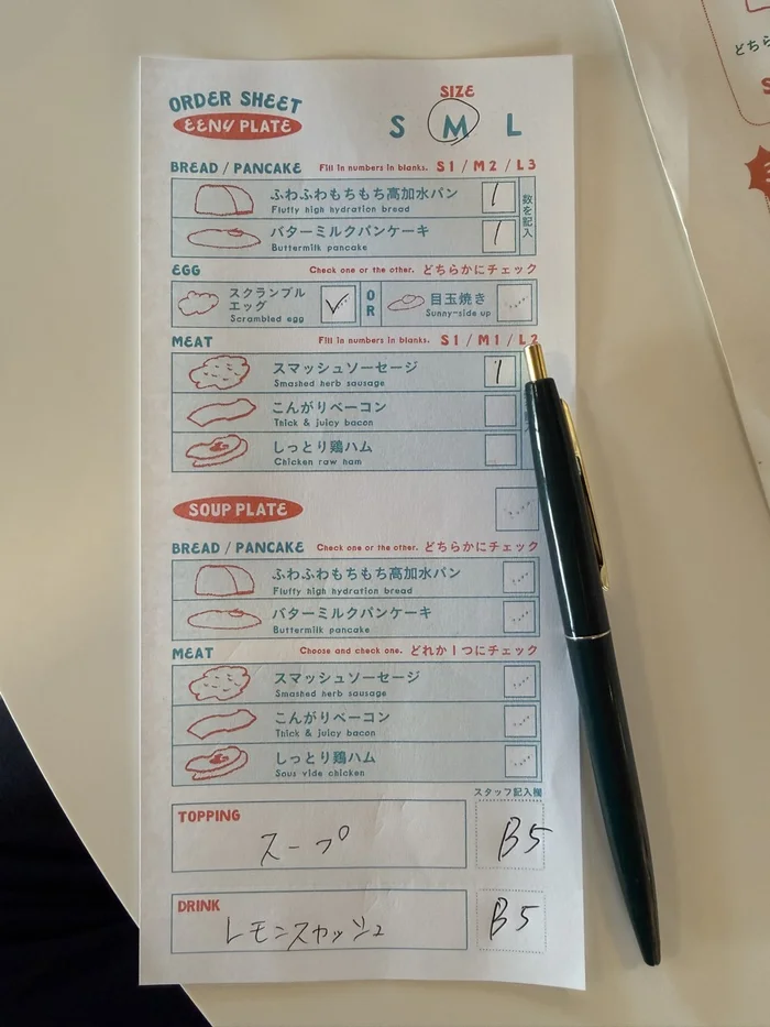 パンや卵、肉の種類を選んで記入する手書きのオーダーシートとペン