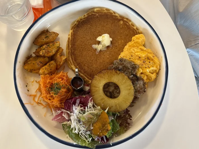 スクランブルエッグとソーセージ、パンケーキ、フライドポテトが盛られたプレート