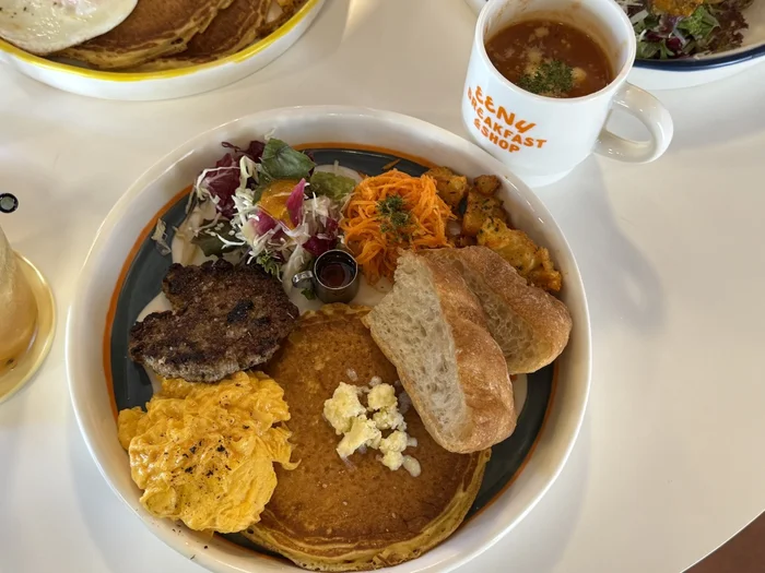 パンとパンケーキ、スクランブルエッグ、ソーセージが盛られたプレートとスープ
