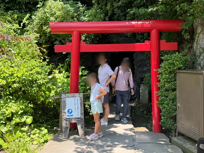 弁天窟の入口に立つ赤い鳥居と洞窟