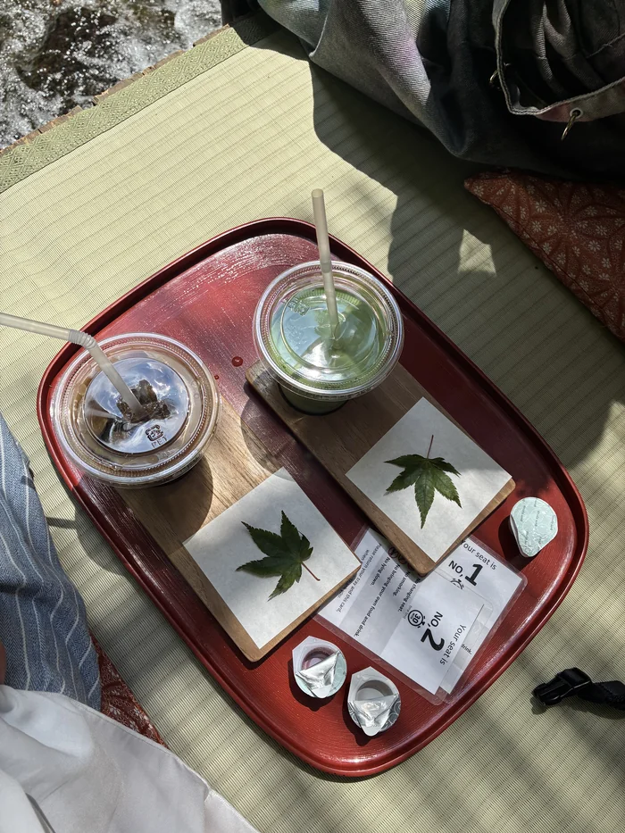 赤いお盆にのったアイスコーヒーとアイス抹茶ラテ、座席番号の札
