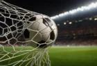 ナイターのスタジアムでゴールネットに突き刺さるサッカーボール