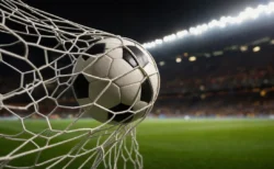 ナイターのスタジアムでゴールネットに突き刺さるサッカーボール