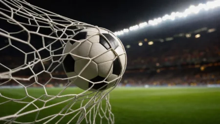 ナイターのスタジアムでゴールネットに突き刺さるサッカーボール