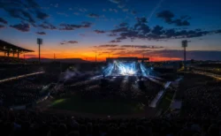夕暮れの野球場で開催された大規模野外ライブ、照明とスモークに照らされたステージと観客