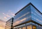 モダンなガラス張りの企業本社ビルを見上げた写実的な情景、夕暮れの反射光