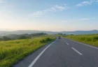 緑の丘陵地帯を通る道路を遠くへ走る車