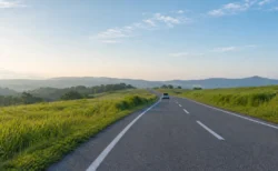 緑の丘陵地帯を通る道路を遠くへ走る車