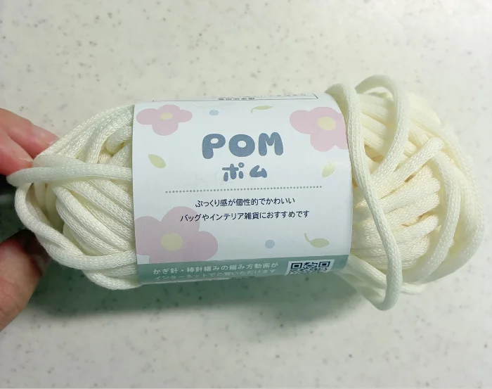 画像 キャンドゥで購入したポム(POM)の毛糸1玉。白い花柄のラベルが巻かれている