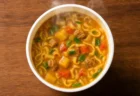湯気の立つカレー風味のカップ麺を上から見下ろしたアングル