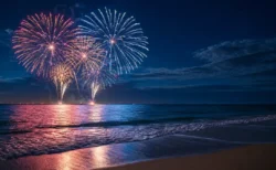 夏の夜、海辺で打ち上がる花火の写実的な情景。人物・文字なし