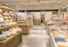 百貨店の催事場に設けられた期間限定グッズ売り場。木目の什器にぬいぐるみや雑貨が並び、天井のスポットライトが商品を照らしている