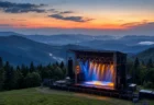 山あいの高原に立つ夏フェスの野外ステージと夕暮れの空