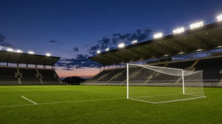 サッカースタジアムのピッチとゴールネット、夕方のナイター照明のイメージ
