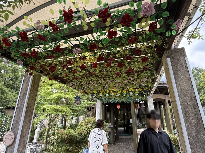 色とりどりのガラスのバラが頭上を覆うローズガーデンのアーチ