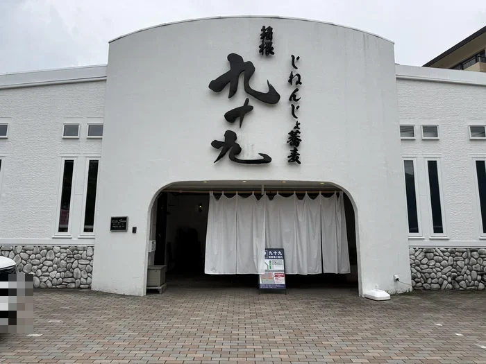 白い外壁に黒い九十九の店名が掲げられたじねんじょ蕎麦 箱根 九十九の正面入口