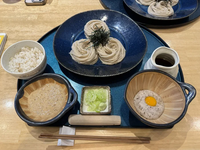 冷たい蕎麦、二種類の自然薯、麦ご飯、薬味が青い盆に並ぶじねんじょとろろ蕎麦御膳