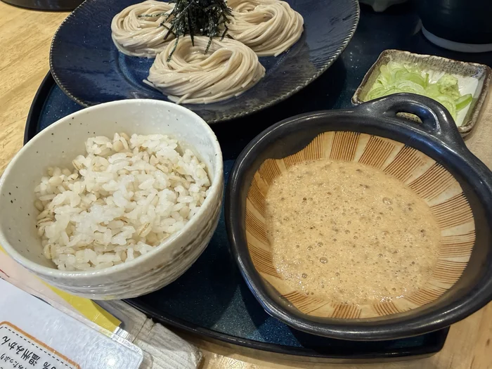 泡立った自然薯とろろ、麦ご飯、冷たい蕎麦が並ぶ御膳のアップ