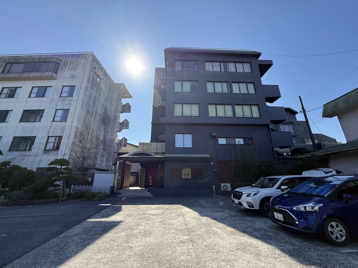 画像 濃紺の外壁に浜紫の看板が掛かった5階建ての宿の外観