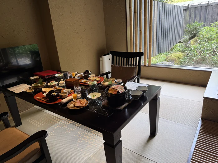 画像 金乃竹 仙石原の客室にある食事スペース。大きな窓の外に竹垣と緑が広がる