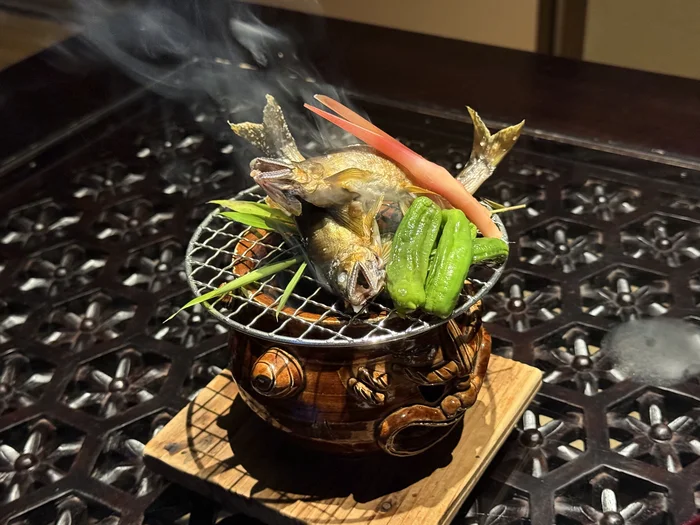 焼き網を渡した器の中から煙が立ちのぼる演出