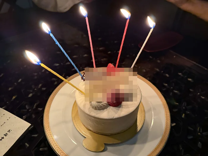 ろうそくを灯して運ばれてきた誕生日ケーキ