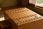 朝の柔らかい光の中に置かれた将棋盤と駒