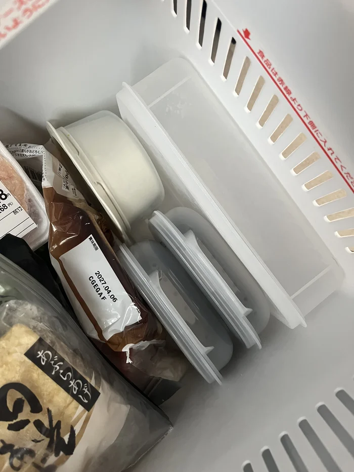 冷凍庫に立てて収納したKITINTOごはん保存容器と、上にある以前使っていた白い容器