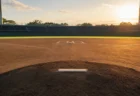 高校野球の球場、マウンドとホームベースを結ぶ夕方の光のイメージ