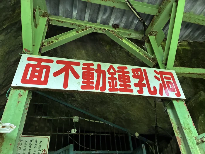 緑色の入口に掲げられた面不動鍾乳洞の赤文字看板