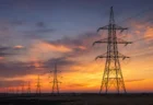 送電線と鉄塔を夕暮れの空を背景に写した写実的な情景