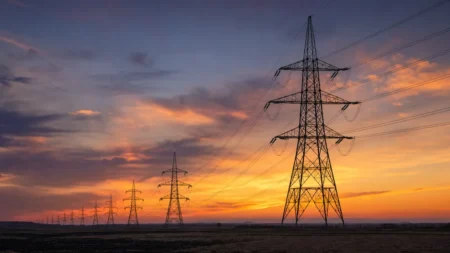送電線と鉄塔を夕暮れの空を背景に写した写実的な情景