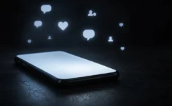 暗闇の中でスマートフォンの画面が光り、SNSの通知アイコンが浮かぶイメージ