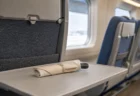 新幹線車内の座席とテーブルに、布と紙で安全に梱包された刃物が置かれている情景