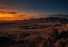 オレンジと紺のグラデーションに染まる荒野の夕景、岩山のシルエット